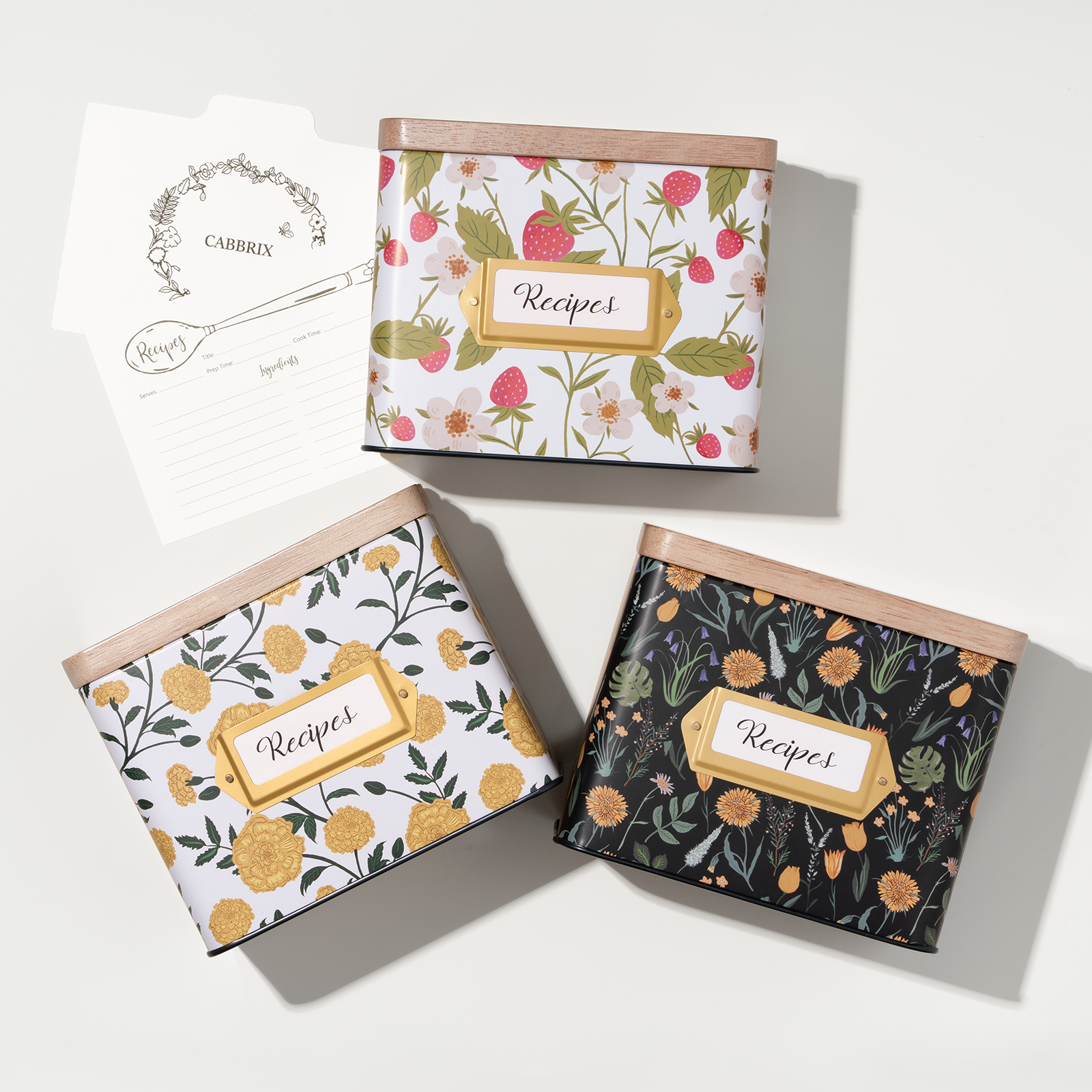 Three recipe books with floral designs on a white background