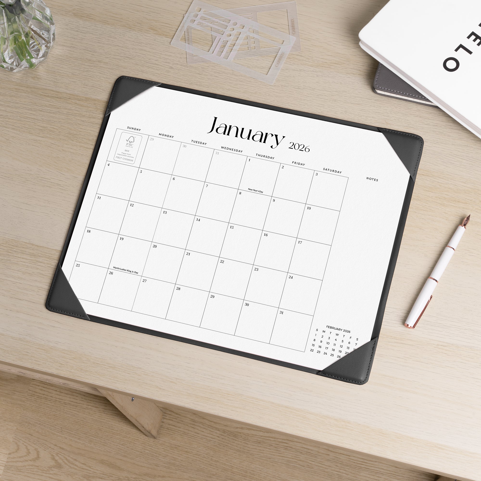 Calendar mat on a desk with a pen and glass of water