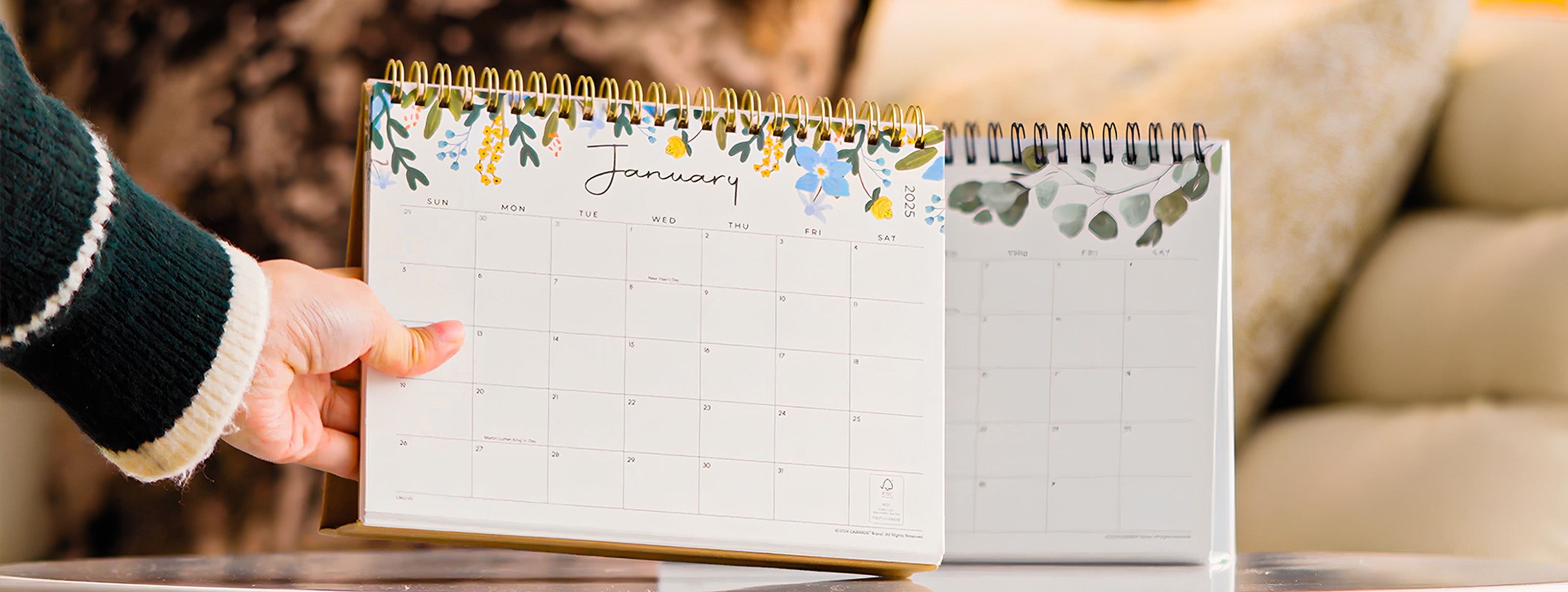 Hand holding a calendar with floral design on a blurred background